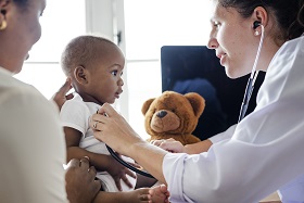 Pediatrician using stethoscope on infant